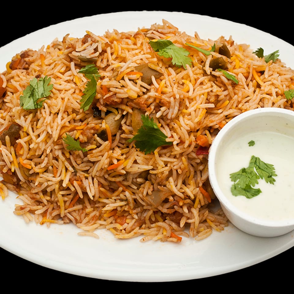 Bombay Kitchen's Indian biryani, a flavorful rice dish with vegetables and cilantro, served with raita.